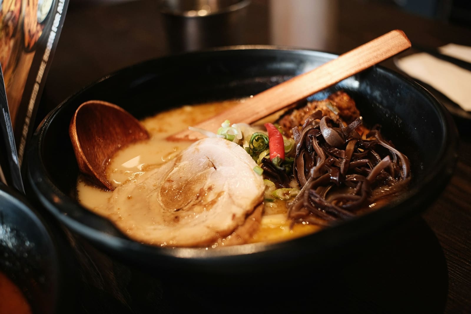 Bol de ramen tonkotsu fumant dans la pénombre